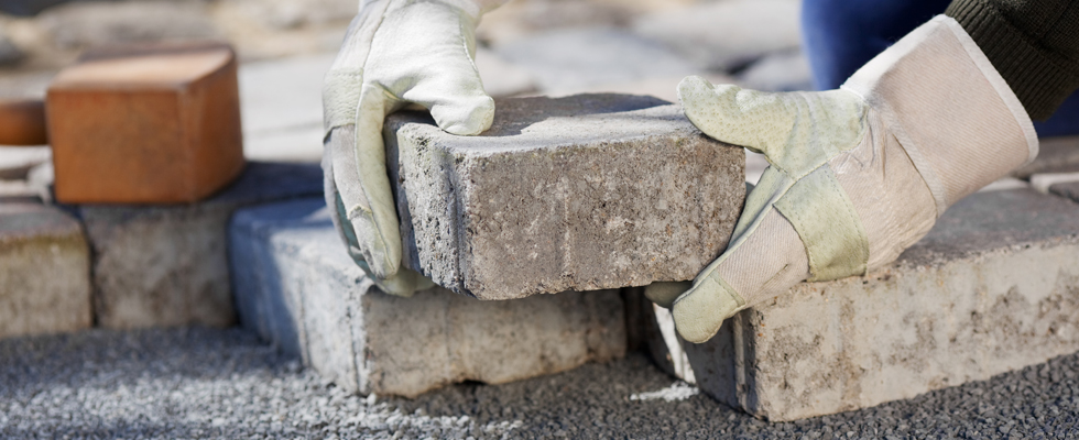 Worker carefully laying bricks for a driveway